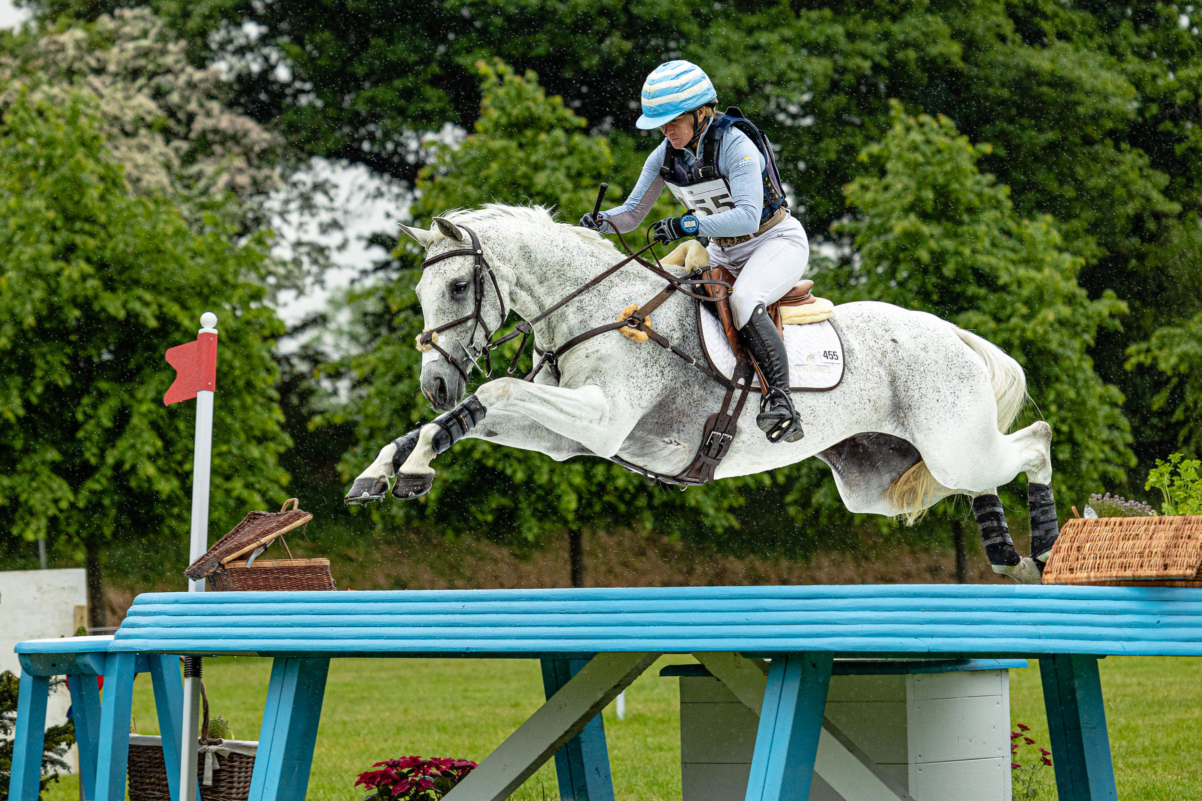 Event photography imge of an event rider jumping a cross country jump on a grey competition horse