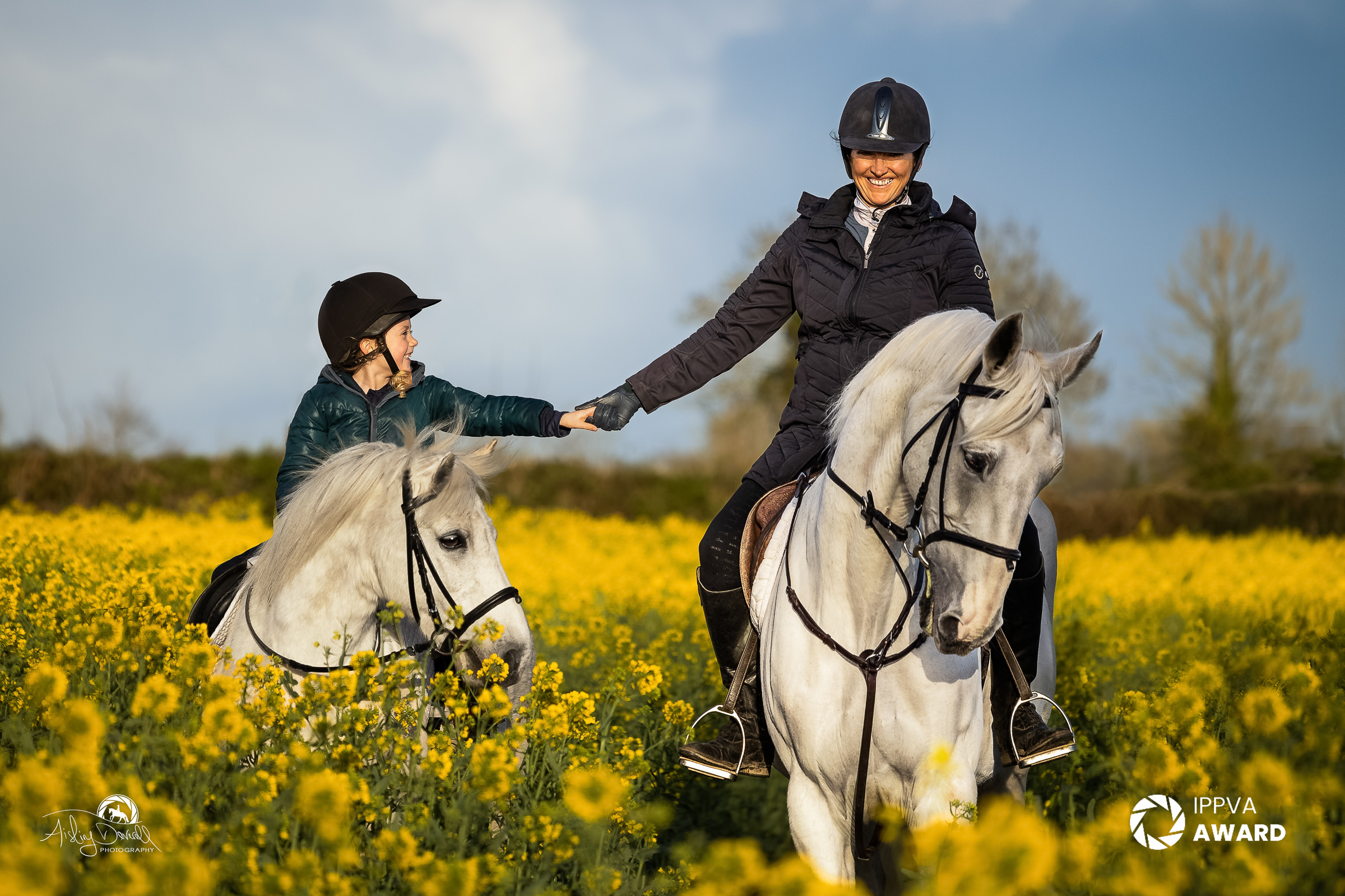 award winning portrait of a mother and daughter on horses in a field of flowers